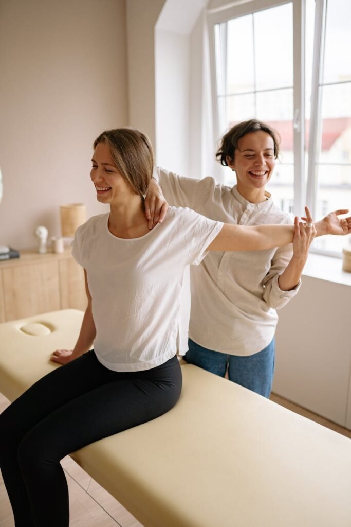 a woman sitting on the therapy bed while stretching her arm